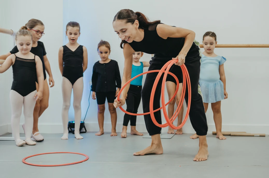 Profesora de baile haciendo ejercicios de movimiento creativo con niños